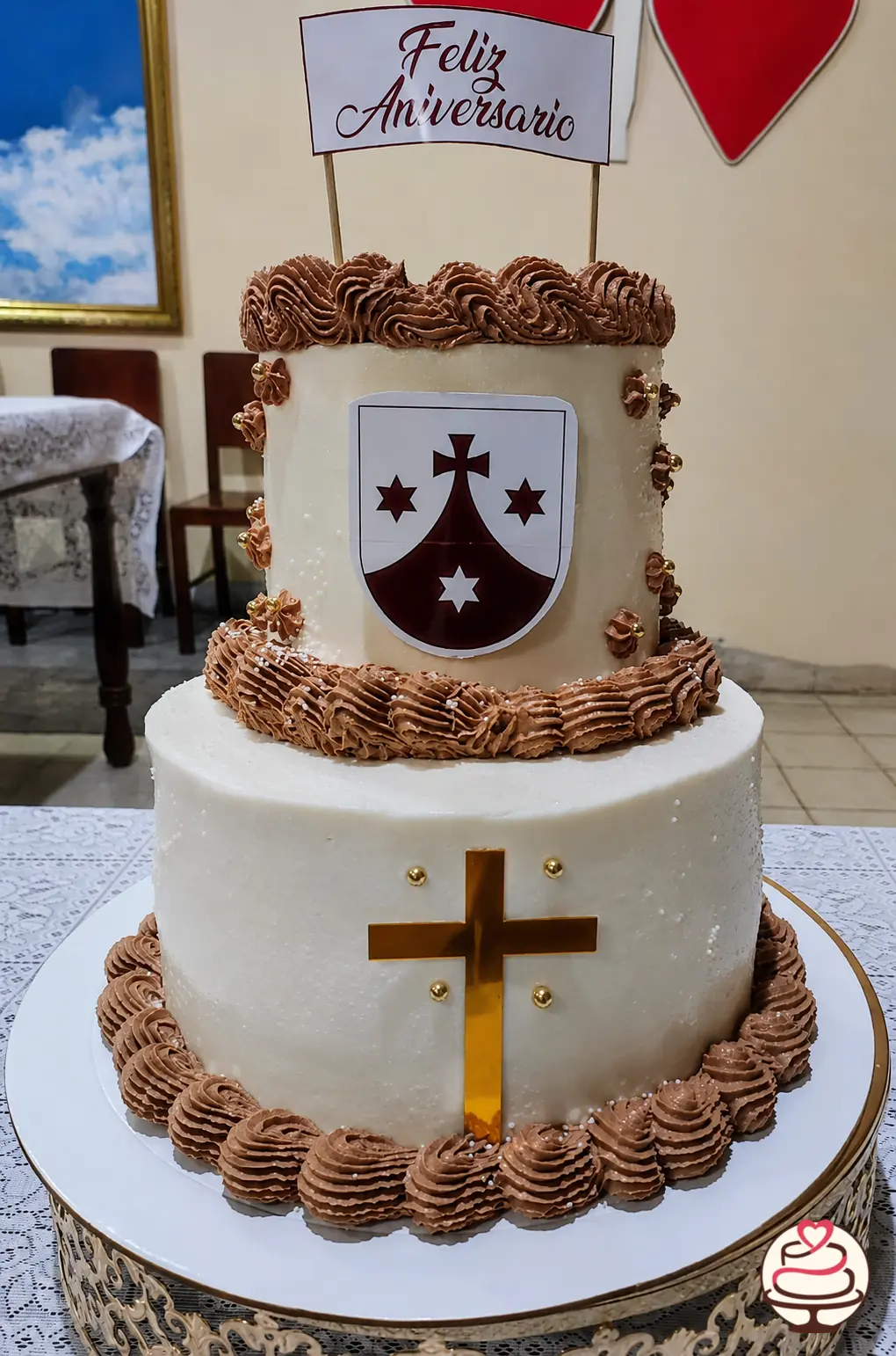 Torta de dos pisos para aniversario sacerdotal con cruz y escudo carmelita