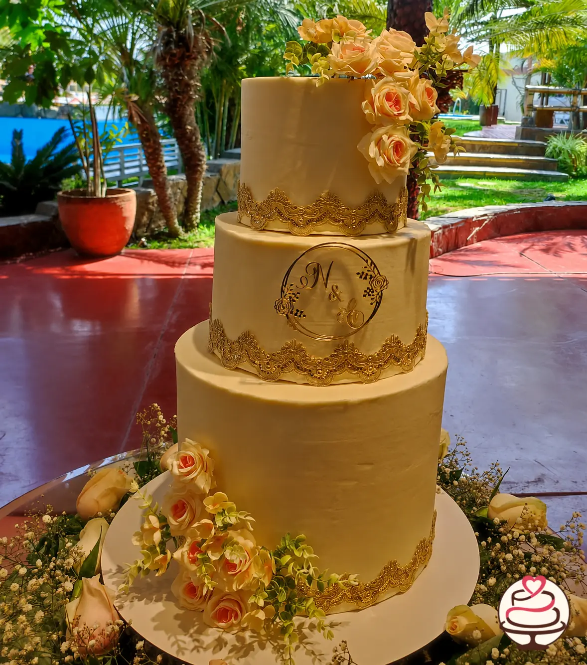 Torta de boda de tres pisos con flores y detalles dorados