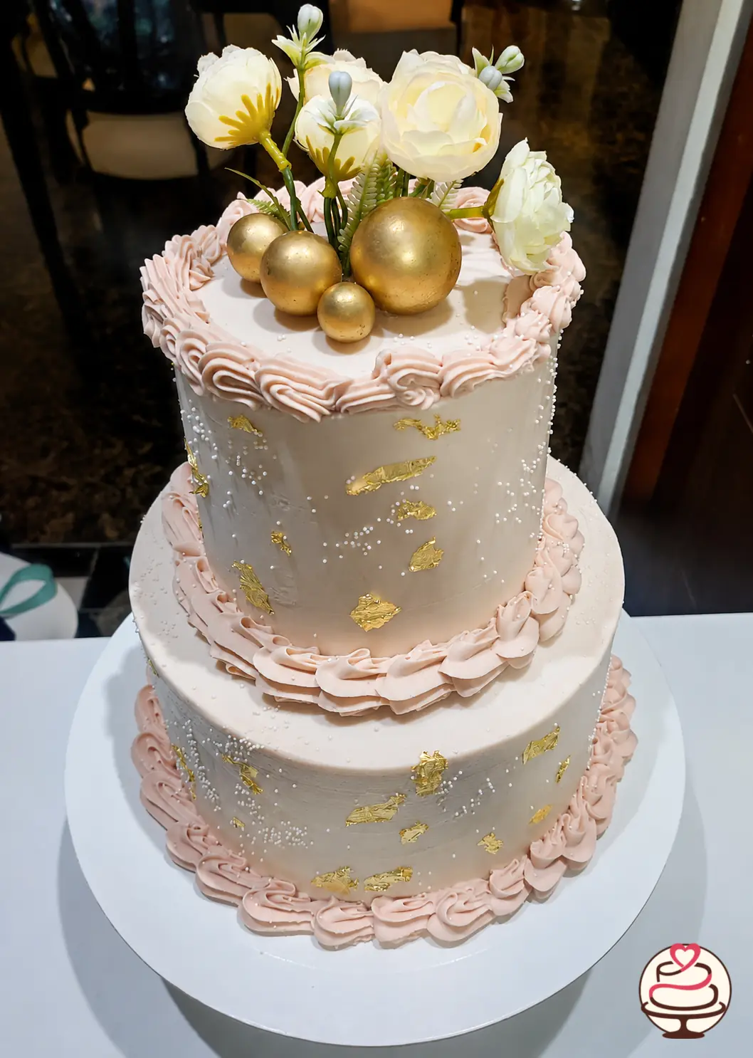 Torta de dos pisos en tonos rosados y dorados con flores