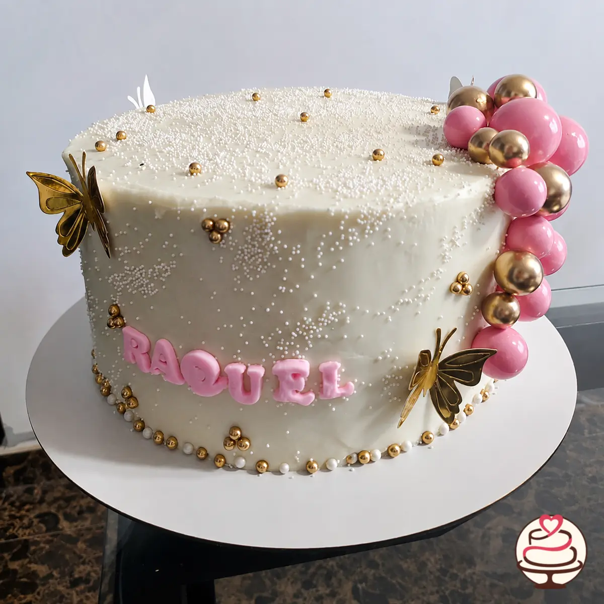 Torta rectangular blanca con esferas rosadas y doradas