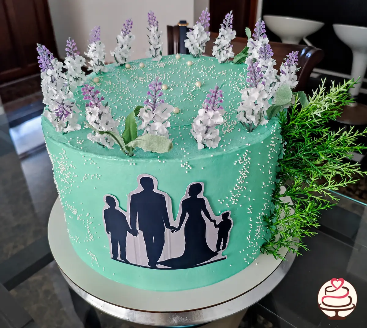 Torta verde agua de aniversario con flores y silueta familiar